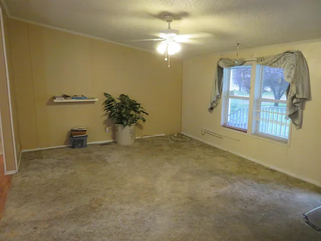 an empty room with windows and ceiling fan