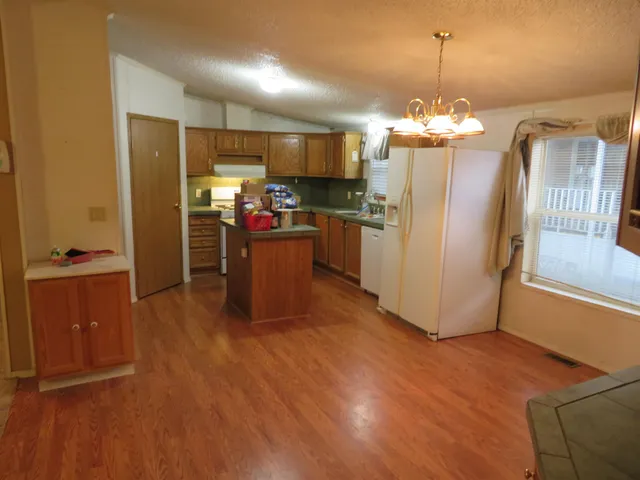 a view of a kitchen with refrigerator and wooden floor
