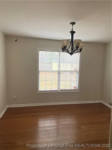 a view of an empty room with wooden floor cabinet and a window