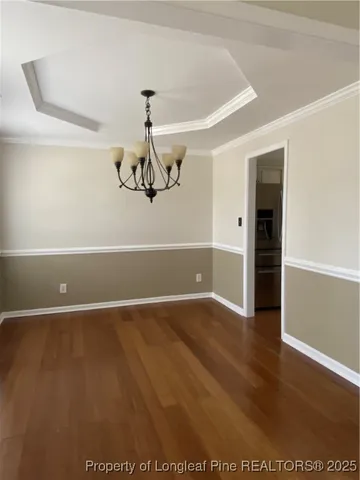 an empty room with wooden floor chandelier fan and windows