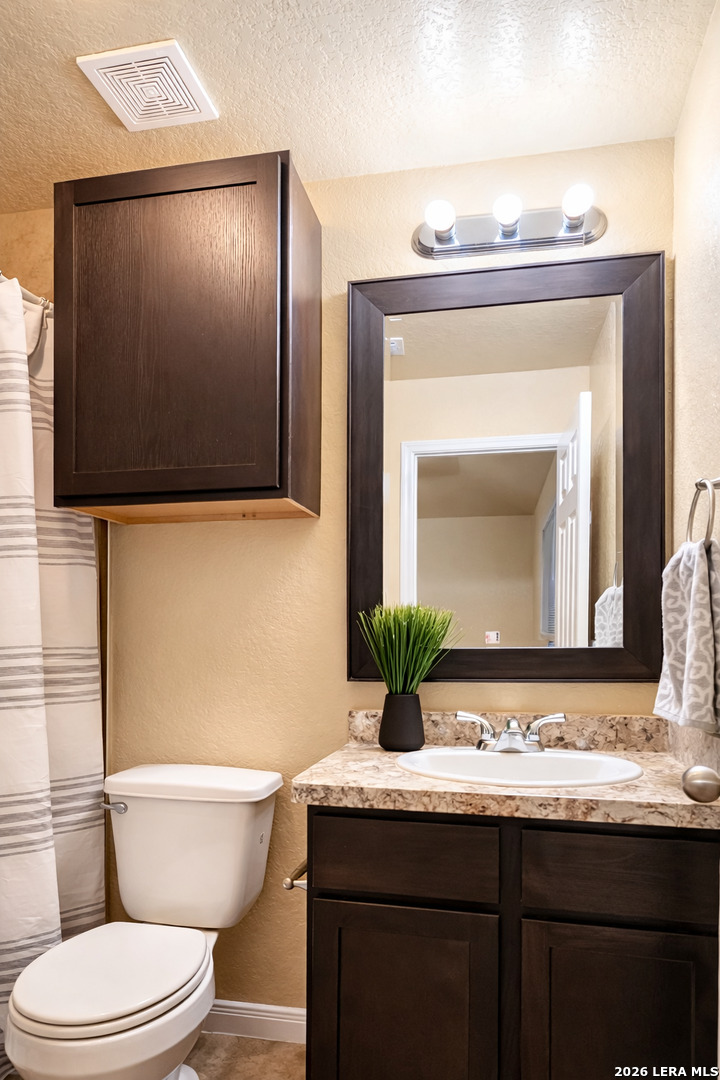 8711 8th Street, Unit 1 Converse, TX 78109 - Photo 14 of 25 a bathroom with a granite countertop toilet sink and mirror
