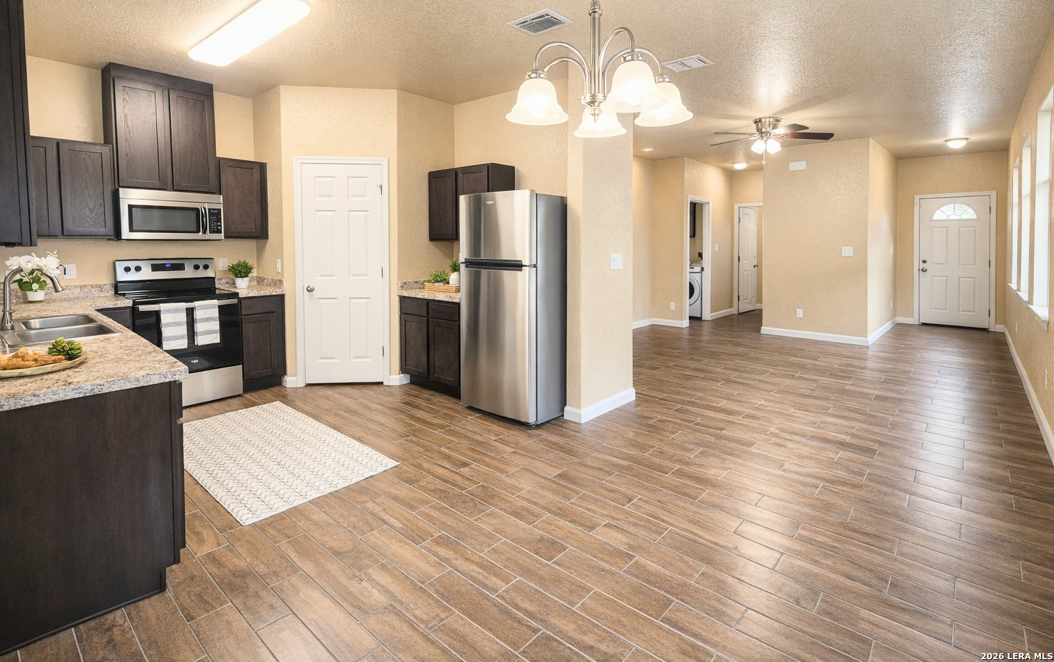 8711 8th Street, Unit 1 Converse, TX 78109 - Photo 5 of 25 a kitchen with stainless steel appliances kitchen island granite countertop a refrigerator oven a sink dishwasher and a refrigerator with wooden floor