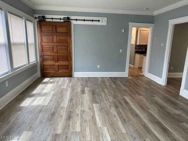 1388 Brookline Road Cleveland, OH 44121 - Photo 8 of 30 Empty room featuring a wealth of natural light, dark hardwood / wood-style flooring, a barn door, and crown molding