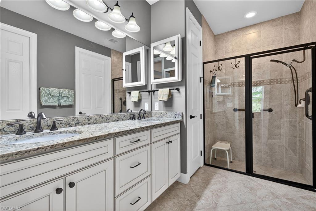 20105 Torch Key Way Estero, FL 33928 - Photo 16 of 29 a bathroom with a granite countertop sink a mirror and a shower