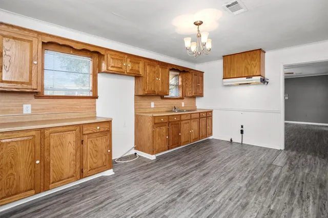 a kitchen with stainless steel appliances granite countertop a stove top oven a sink dishwasher and a refrigerator with wooden floor