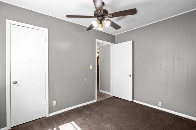 an empty room with a ceiling fan and a window