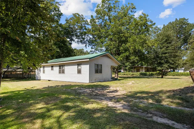 a view of a house with a yard and large trees