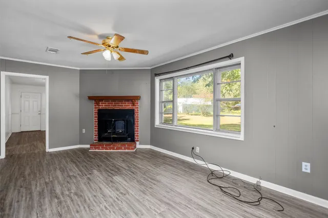 a view of an empty room with a window and wooden floor