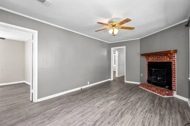 an empty room with wooden floor a chandelier fan and windows