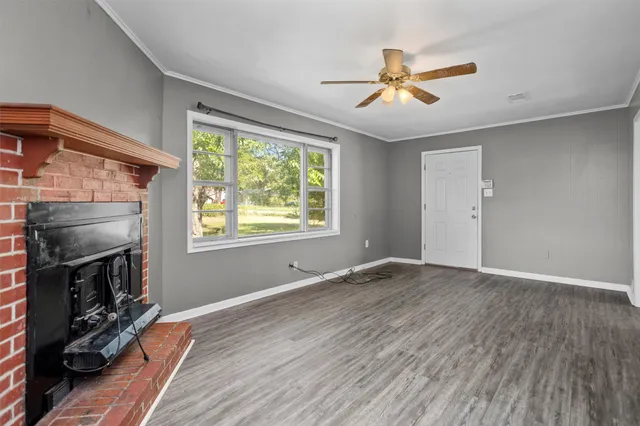a view of empty room with wooden floor fireplace and a window