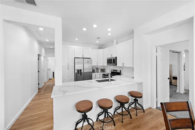 a kitchen with stainless steel appliances kitchen island granite countertop a dining table chairs refrigerator and sink