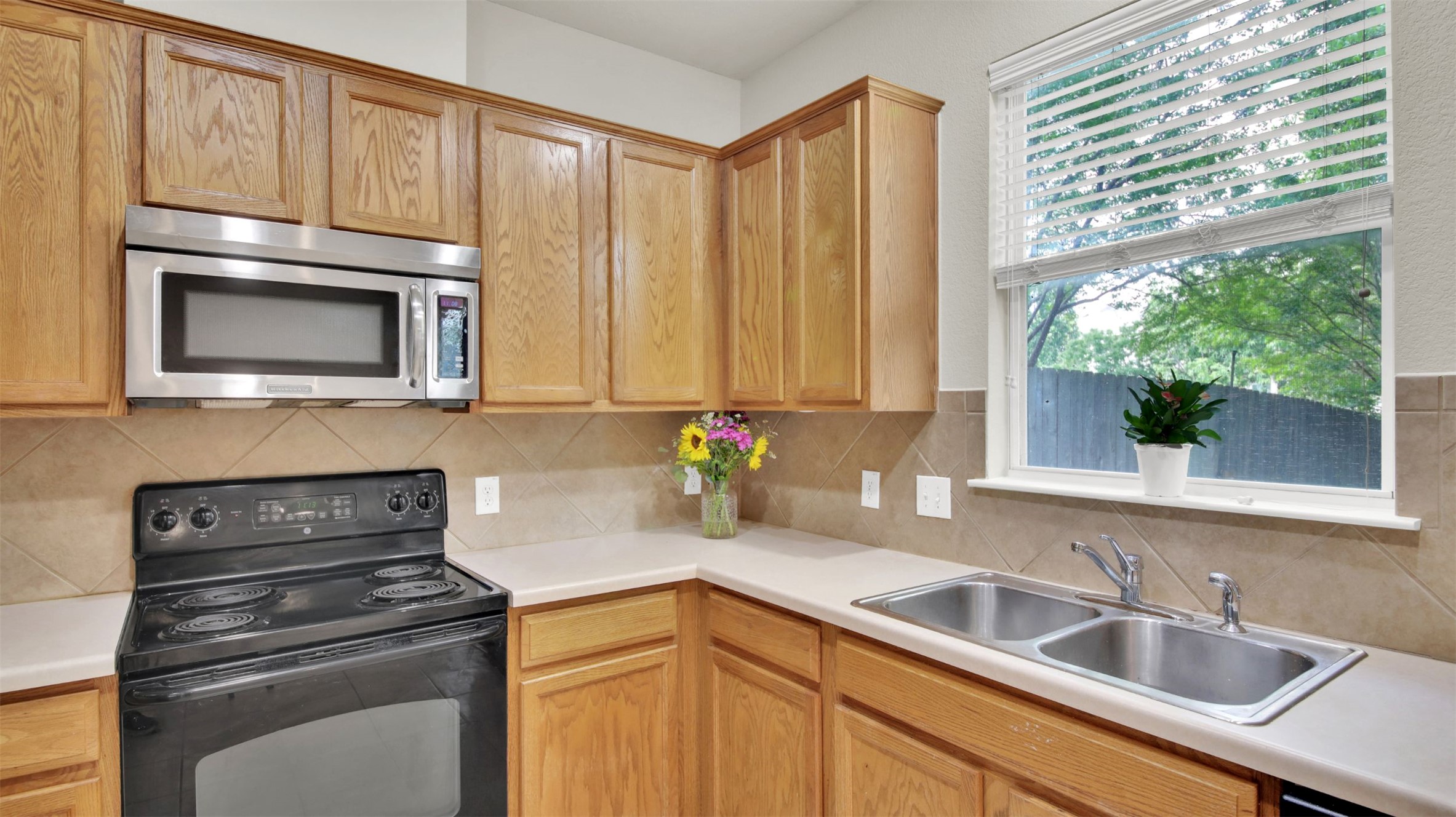 73 Verde Ranch Loop Leander, TX 78641 - Photo 12 of 29 Kitchen featuring light countertops, backsplash, a sink, and black appliances
