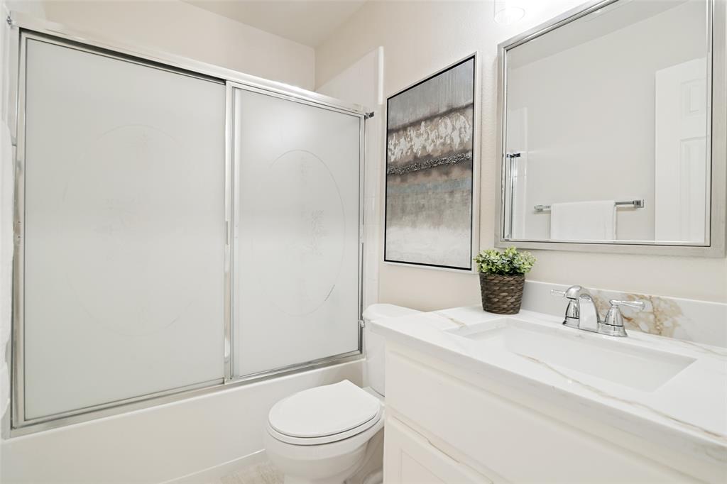 3020 Ridge Hollow Drive Plano, TX 75023 - Photo 17 of 28 Bathroom featuring a frosted glass tub enclosure, a white vanity with a rectangular undermount sink, a polished chrome faucet, and a wall-mounted mirror with a brushed nickel frame