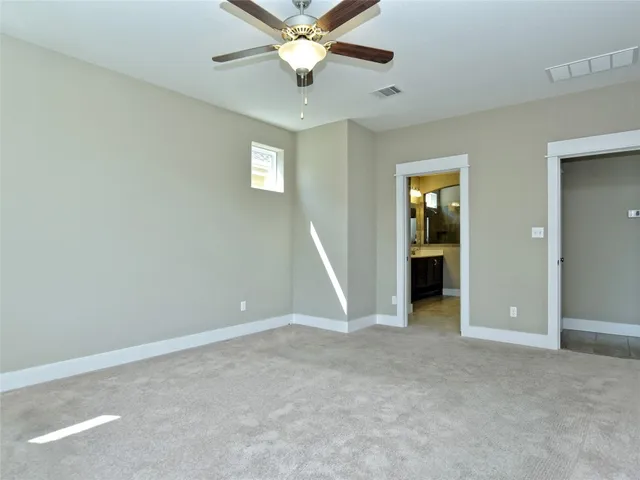 an empty room with a chandelier fan and wooden floor