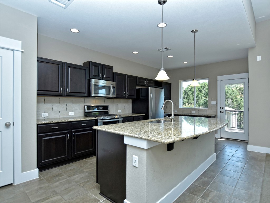 721 Clear Stream Crossing Austin, TX 78753 - Photo 8 of 24 a kitchen with stainless steel appliances granite countertop a sink a stove top oven a counter space and cabinets