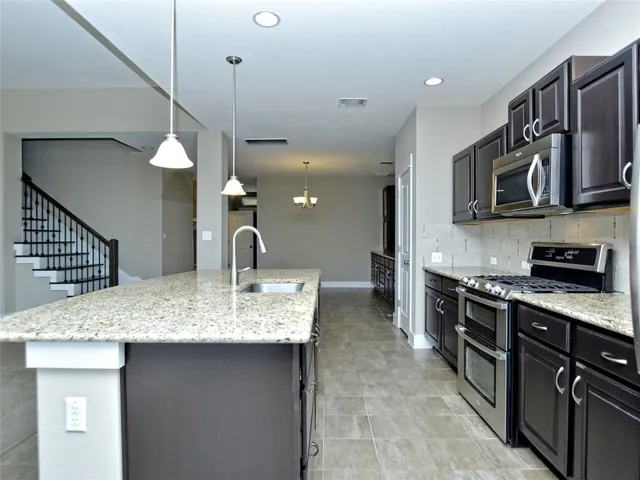 a kitchen with stainless steel appliances granite countertop a sink a stove top oven a counter space and cabinets