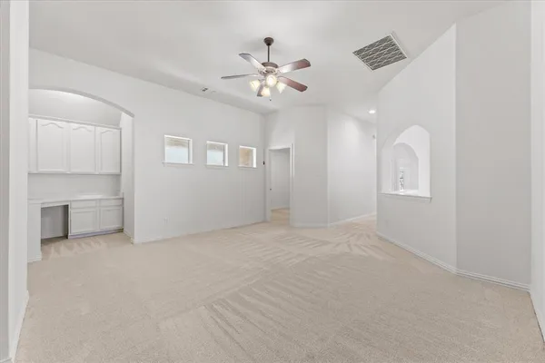 an empty room with chandelier fan and windows