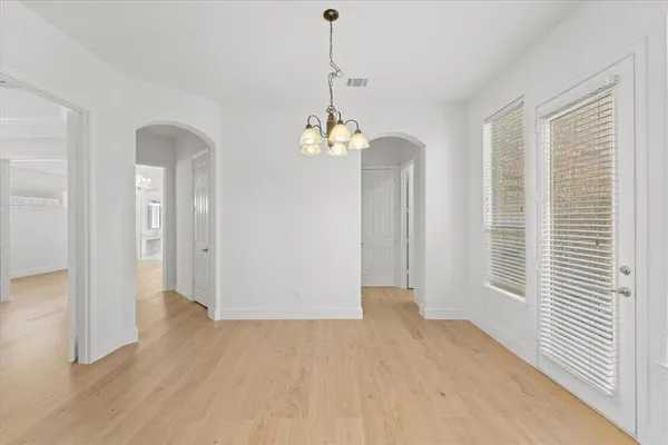 a dining room with wooden floor and a chandelier