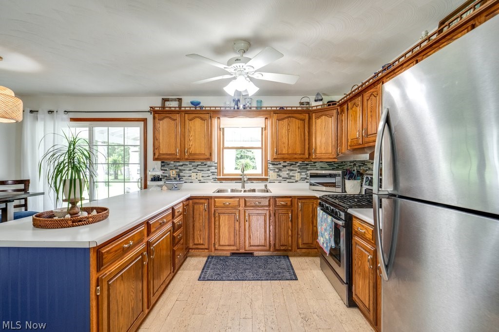 531 Porter Road Atwater, OH 44201 - Photo 29 of 44 Kitchen featuring ceiling fan, light wood-type flooring, backsplash, sink, and appliances with stainless steel finishes