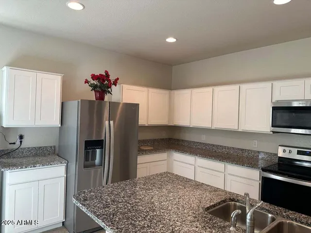 a kitchen with stainless steel appliances granite countertop a refrigerator and a stove top oven