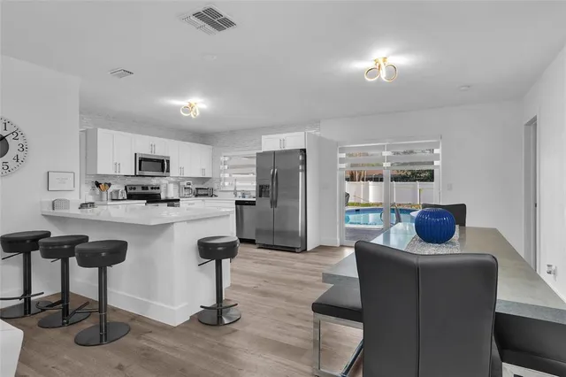 a kitchen with stainless steel appliances kitchen island granite countertop a refrigerator a stove a sink a dining table and chairs