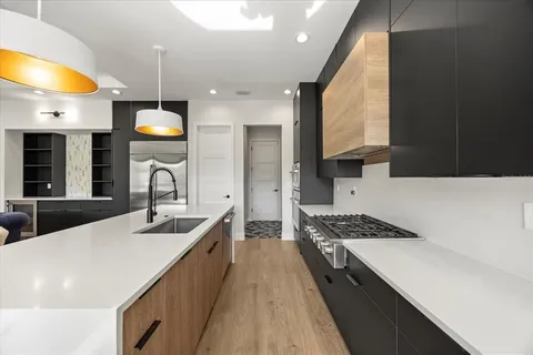 a kitchen with stainless steel appliances a sink a stove and a wooden floors