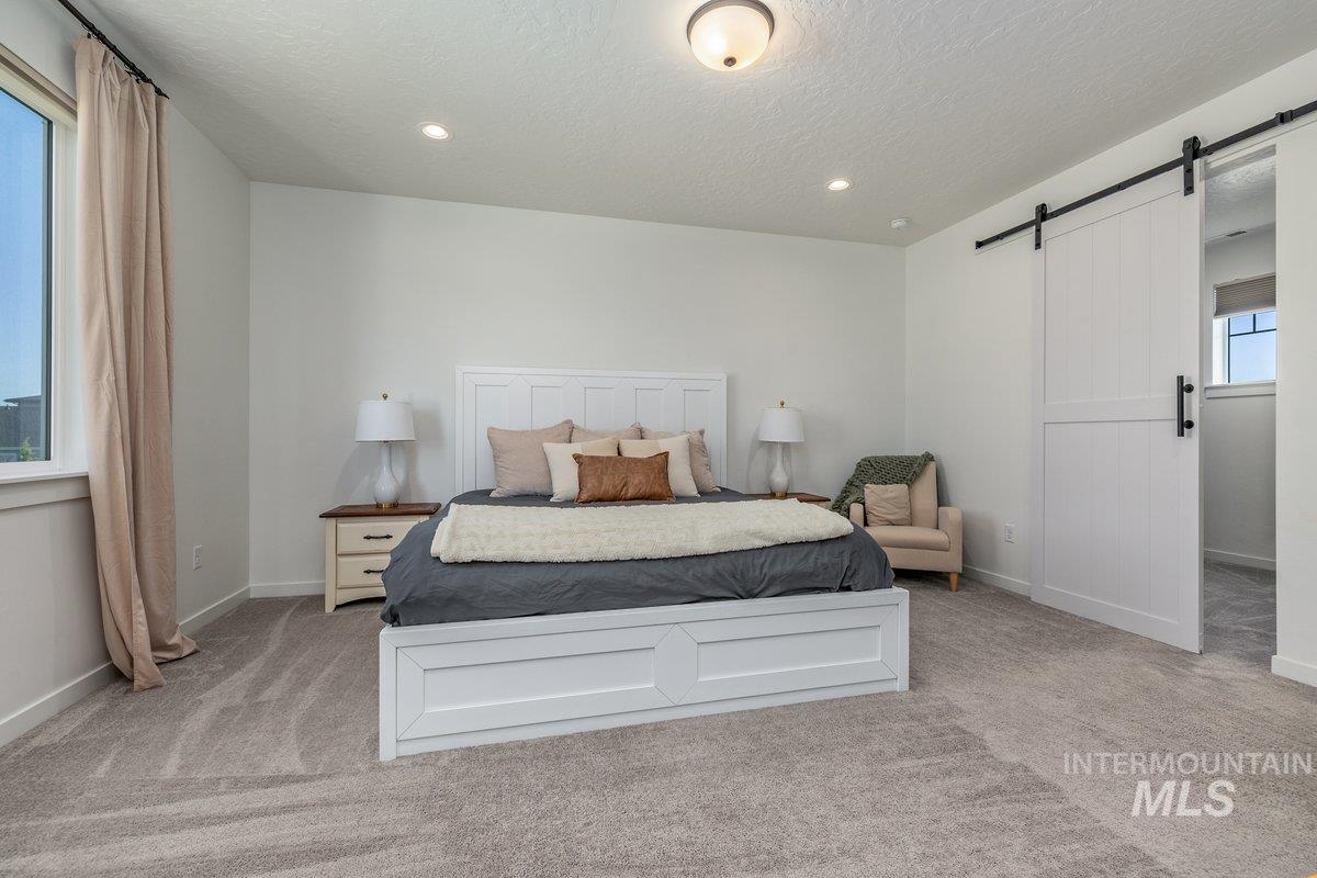 1380 West Chilitna Street Meridian, ID 83642 - Photo 24 of 50 Light gray carpeting provides a neutral foundation for this room featuring a large window, recessed lighting, and a white barn door on a black metal track