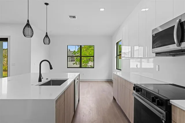 a kitchen with stainless steel appliances a sink a stove and a wooden floors