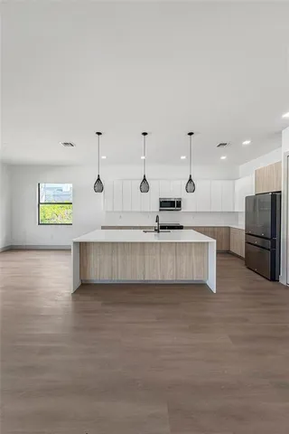 a large kitchen with stainless steel appliances kitchen island a large counter top and a wooden floor