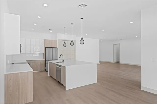 a large kitchen with stainless steel appliances a large counter top a refrigerator a sink and a stove