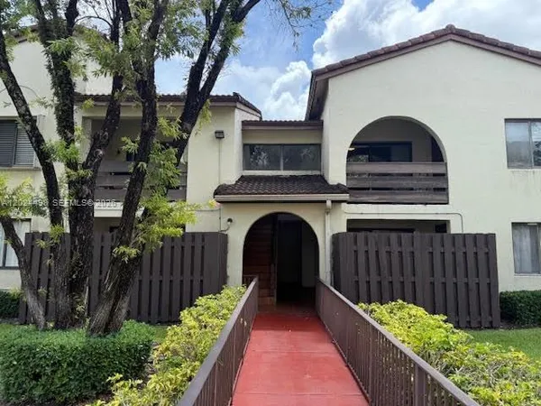 a view of a house with wooden fence and a large tree