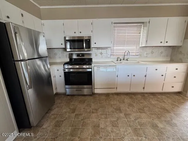 a kitchen with granite countertop a refrigerator sink and white cabinets