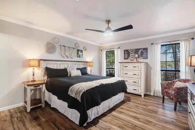a bedroom with a bed and dresser with wooden floor
