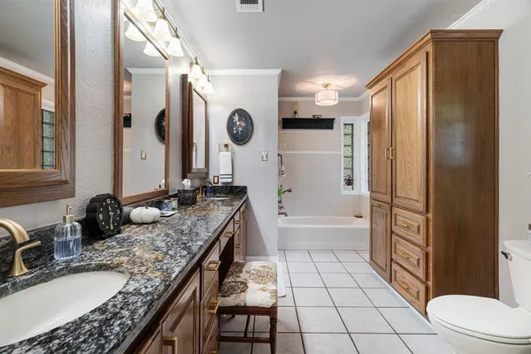a bathroom with a granite countertop sink a toilet and shower