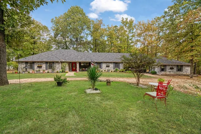 a front view of a house with garden and trees