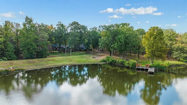 a view of a lake with a yard and large trees