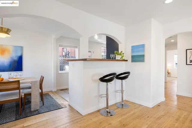 a kitchen with stainless steel appliances a dining table chairs and a refrigerator a stove top oven with wooden floor