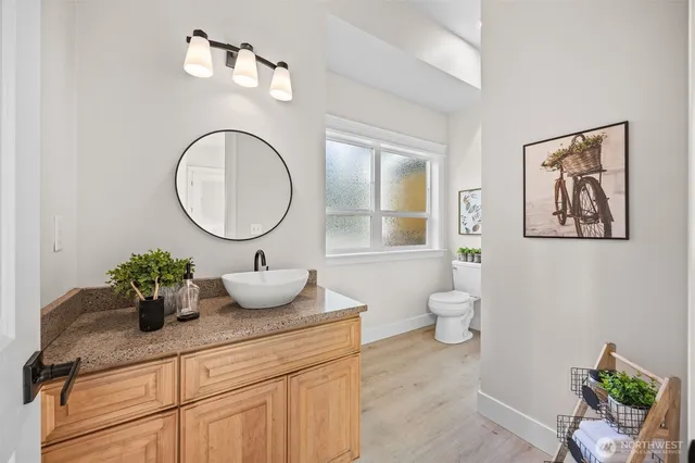 a bathroom with a granite countertop sink mirror vanity and toilet