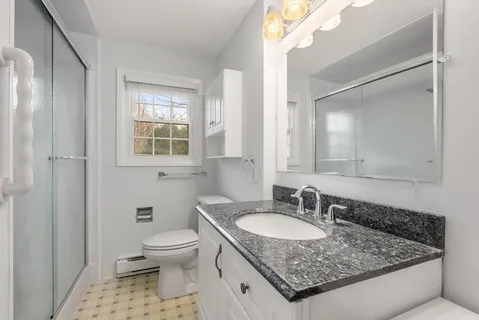 a bathroom with a granite countertop sink a toilet and a mirror