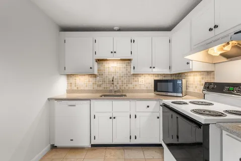 a kitchen with granite countertop white cabinets and white appliances