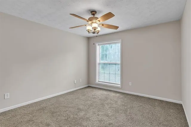 an empty room with window and chandelier fan