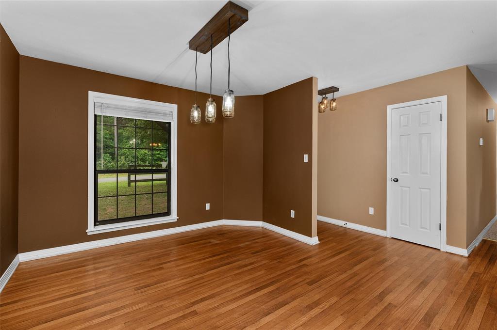 9720 Locust Hill Road Greenwood, LA 71033 - Photo 19 of 31 an empty room with wooden floor chandelier and windows