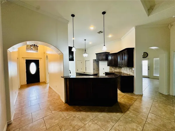 a kitchen with stainless steel appliances kitchen island granite countertop a refrigerator a stove and a wooden floors