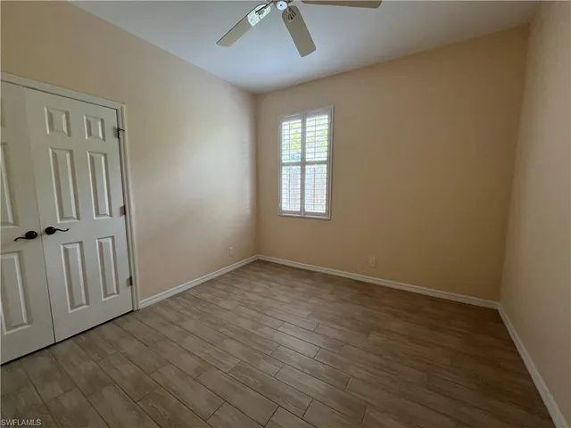 an empty room with wooden floor fan and windows