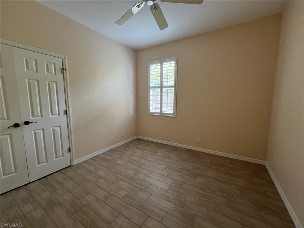 366 Burnt Pine Drive Naples, FL 34119 - Photo 19 of 36 an empty room with wooden floor fan and windows