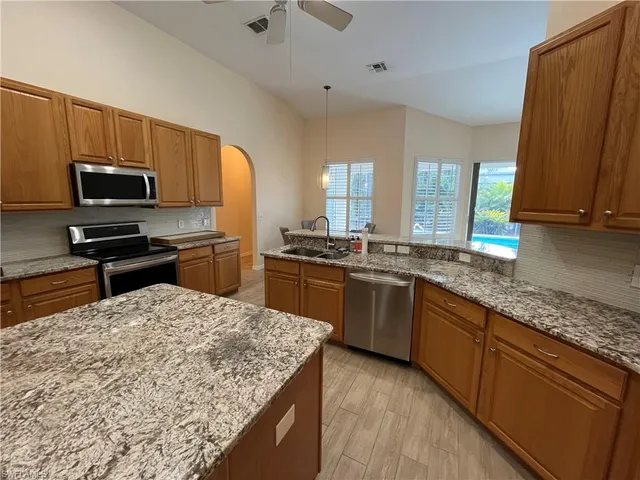 a kitchen with stainless steel appliances kitchen island granite countertop a sink a stove counter space and cabinets