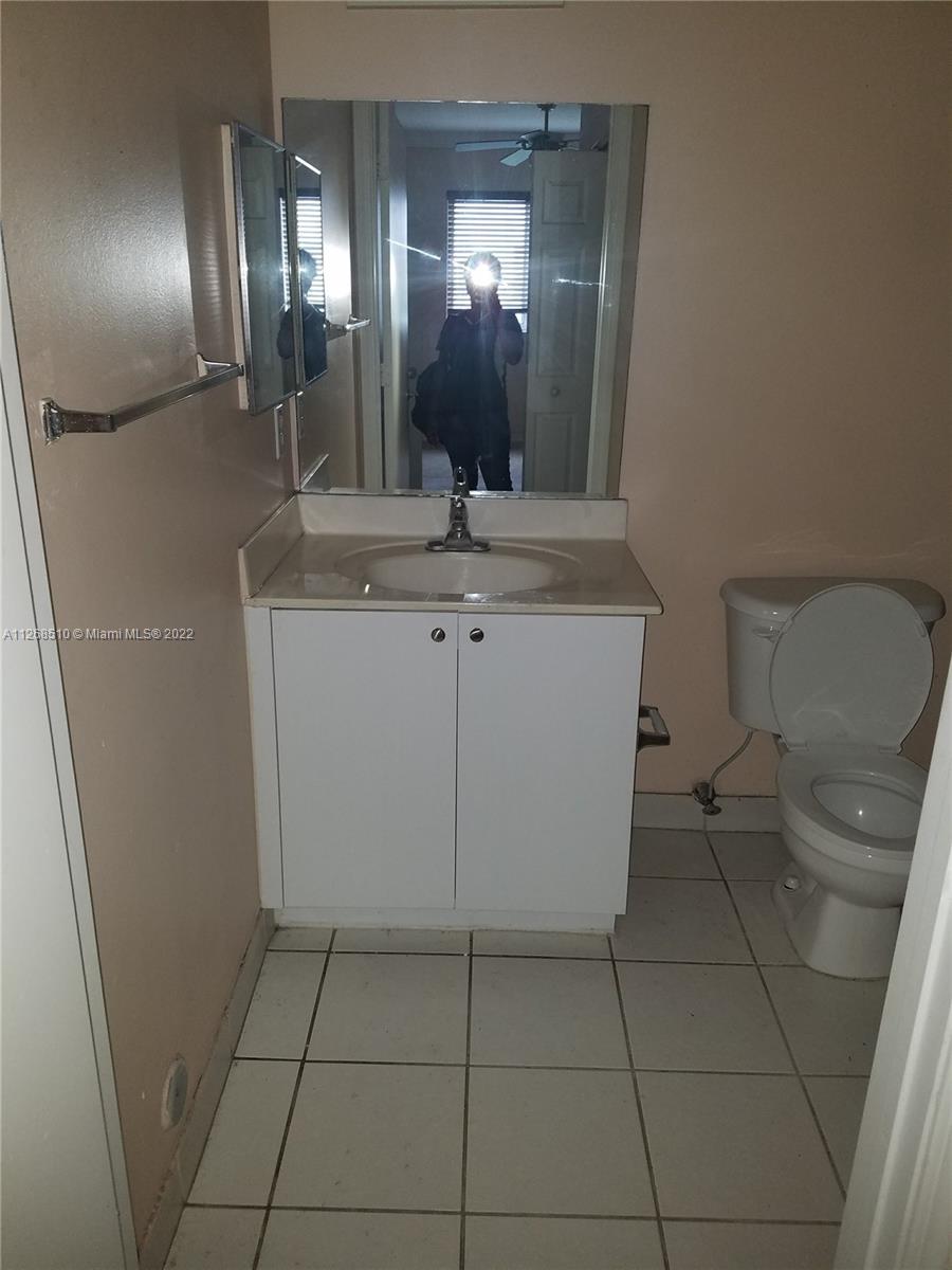 11050 Southwest 196th Street, Unit 305 Miami, FL 33157 - Photo 7 of 9 a bathroom with a toilet a sink a mirror and vanity