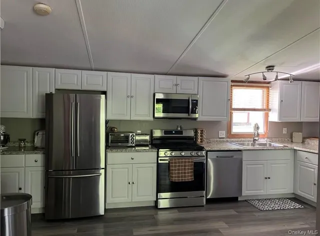 a kitchen with a refrigerator a microwave a sink and cabinets