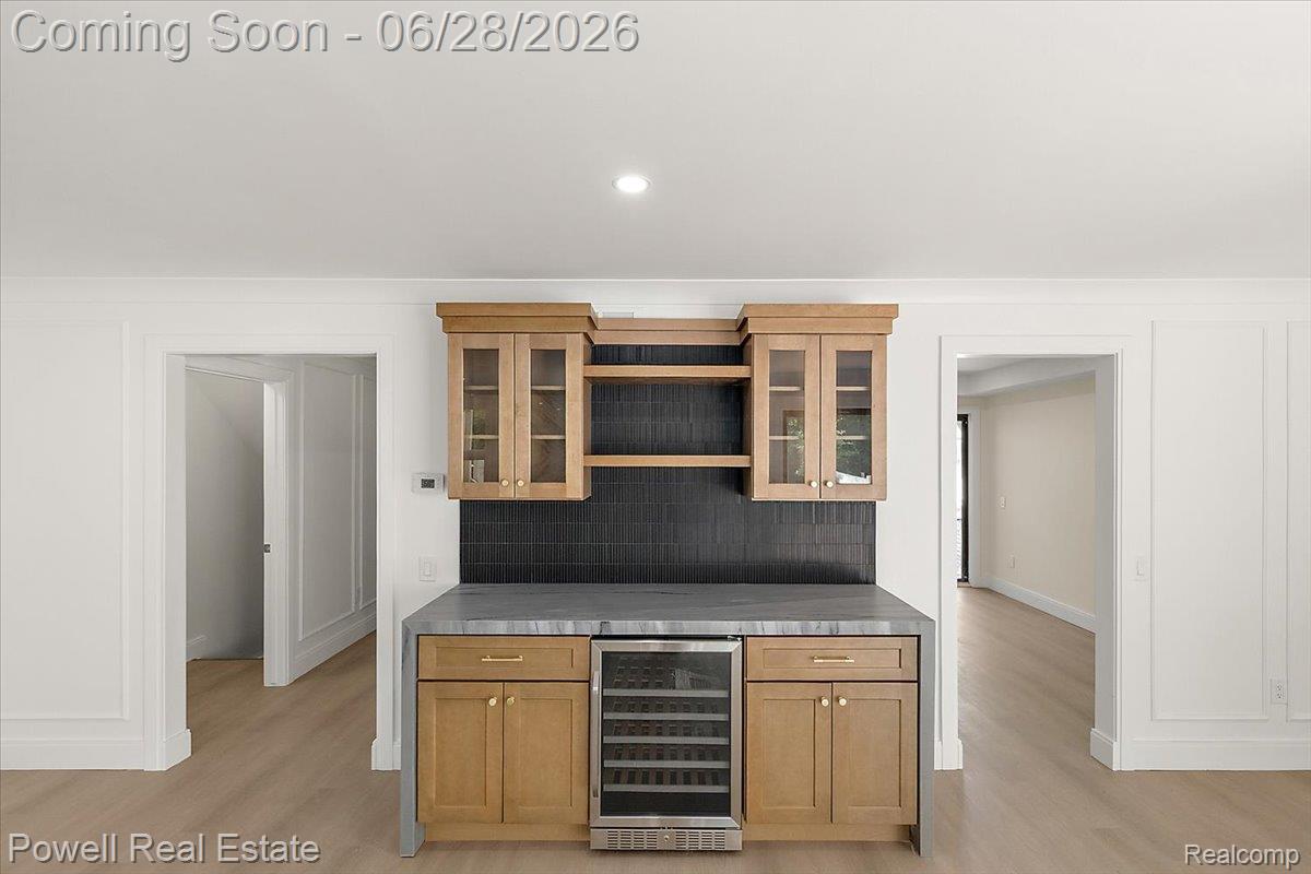 1447 Ravineview Court, Unit C12 Bloomfield Hills, MI 48304 - Photo 17 of 49 Built-in bar area featuring light wood cabinetry with glass-front uppers, a dark tile backsplash, and a wine refrigerator