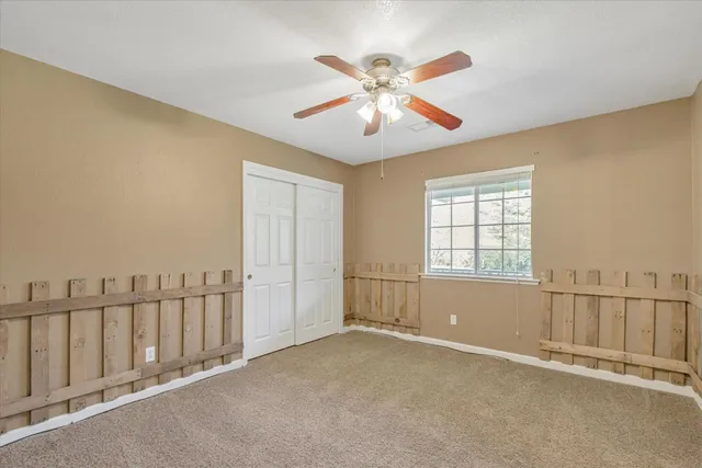 an empty room with windows & a ceiling fan